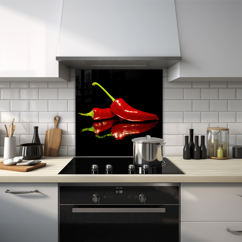 Glass splashback displaying two wet red chili peppers on green powder against a black backdrop.