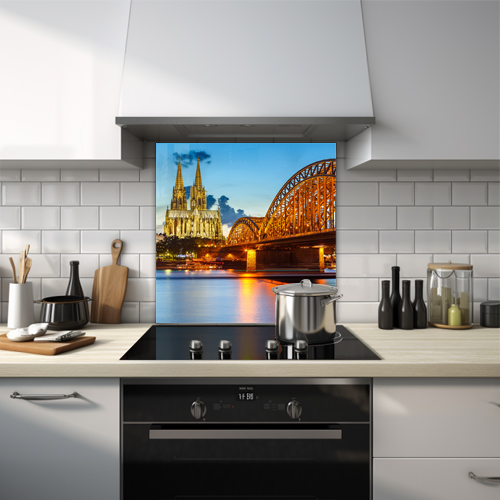 Hohenzollern Bridge in Cologne, Germany at night with a church in the background.