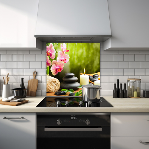 Flower with stacked pebbles and lit candle glass splashback.