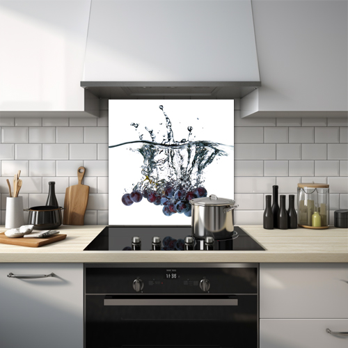 Blue grapes diving into water glass splashback.