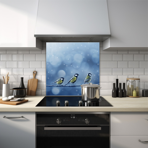 Glass splashback of three great tits on a branch in a snowy winter setting.