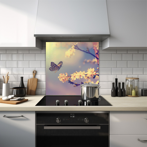 Glass splashback of a butterfly approaching a white blossom tree.