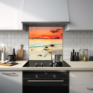 Sun setting over sea with beach rocks and rowing boats glass splashback. thumbnail