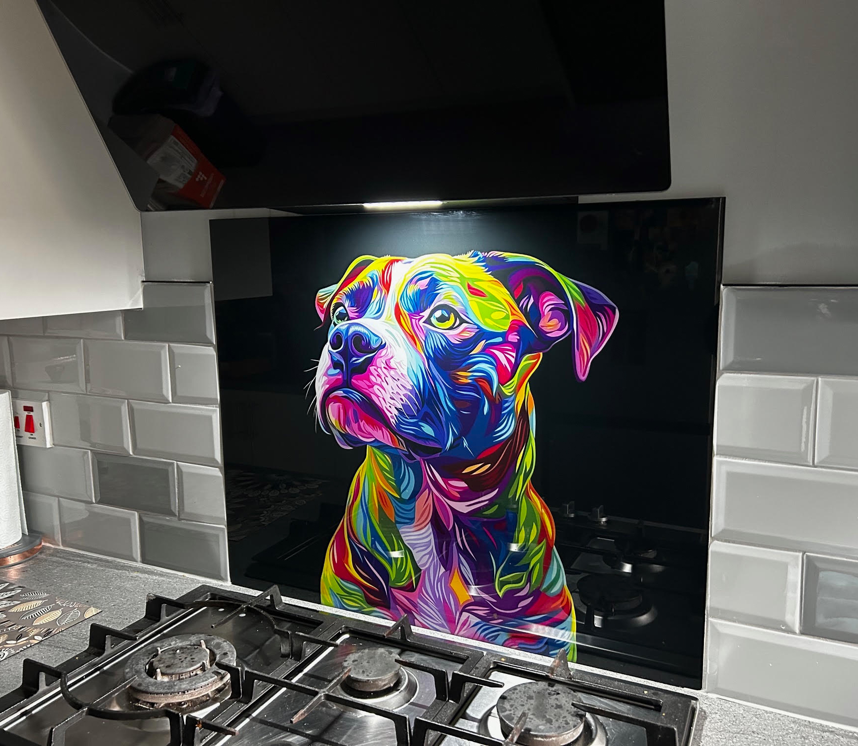 Colourful neon Staffordshire Bull Terrier glass splashback with a black background installed behind a gas hob in Suzanne’s modern white and grey kitchen.